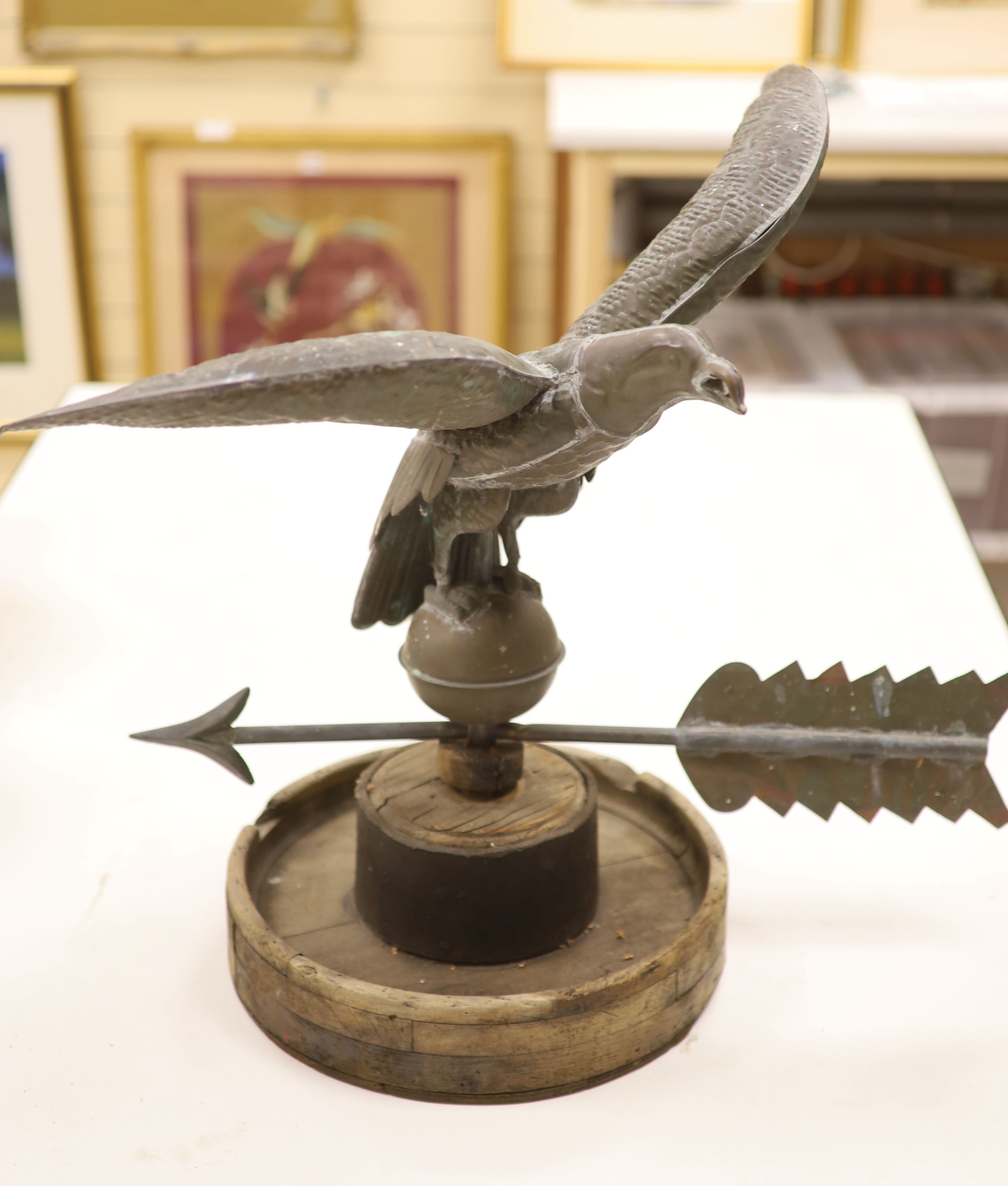 A 19th century American copper weather vane, modelled as an eagle, on an associated wooden base, width 62cm height 58cm